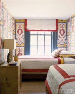 Petite chambre étroite avec deux lits et murs colorés