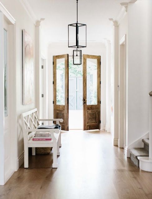 Hall d'entrée blanc et grandes portes d'entrée en bois